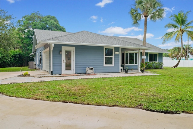 view of front of house with a front yard, central AC, and a garage