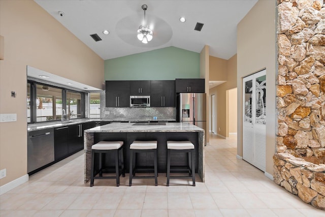 kitchen with ceiling fan, stainless steel appliances, backsplash, a breakfast bar area, and a kitchen island