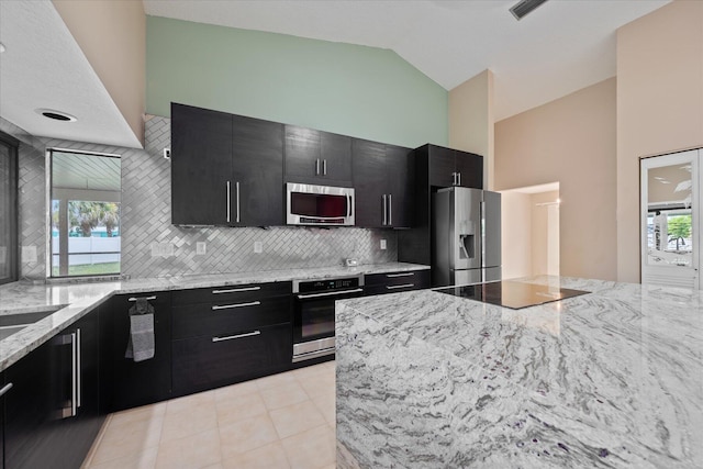 kitchen featuring appliances with stainless steel finishes, lofted ceiling, tasteful backsplash, and a healthy amount of sunlight