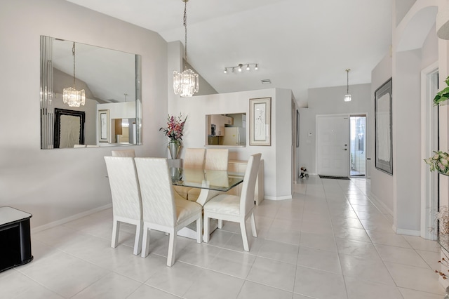 dining area featuring rail lighting, a chandelier, light tile patterned floors, and vaulted ceiling