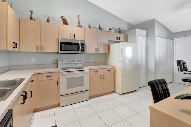 kitchen with light tile patterned floors, stainless steel appliances, light brown cabinetry, and lofted ceiling