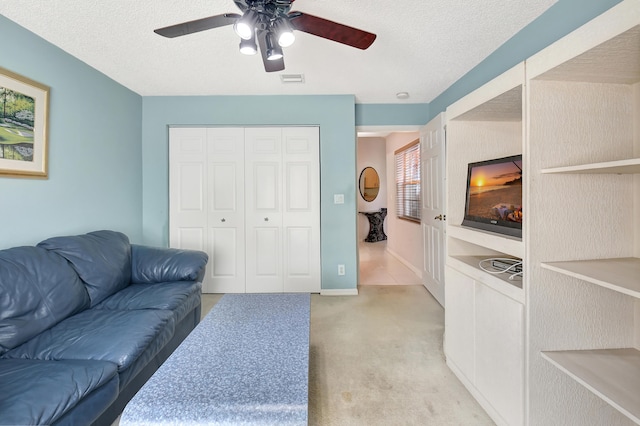 living room with a textured ceiling, light colored carpet, and ceiling fan