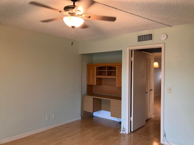 interior space featuring ceiling fan, a textured ceiling, and light wood-type flooring