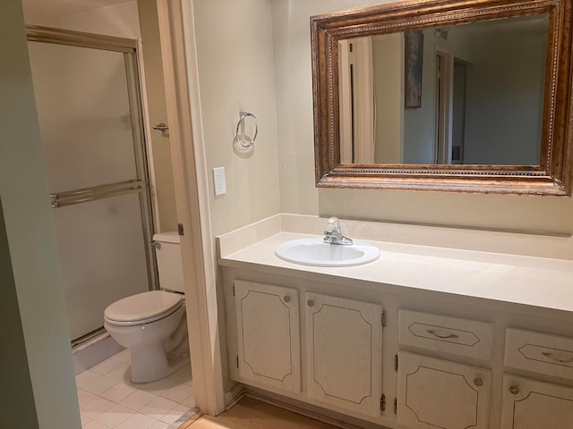 bathroom with vanity, a shower with shower door, toilet, and tile patterned floors