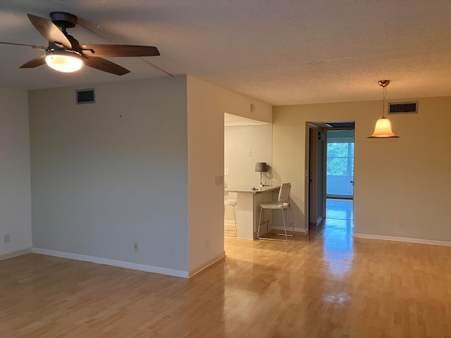 unfurnished room featuring light hardwood / wood-style flooring, a textured ceiling, and ceiling fan