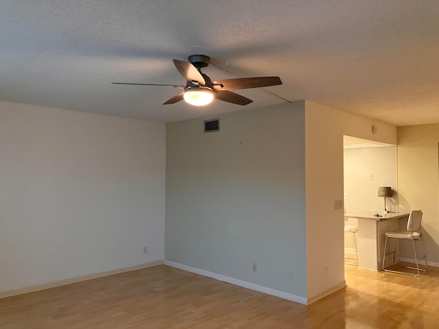 spare room featuring a textured ceiling, light wood-type flooring, and ceiling fan