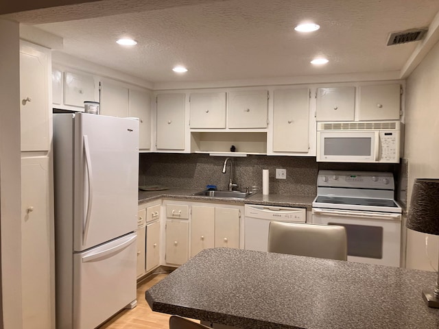 kitchen featuring white appliances, sink, white cabinetry, decorative backsplash, and light hardwood / wood-style flooring