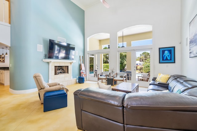 living room with ceiling fan, a high ceiling, french doors, a fireplace, and light tile patterned flooring