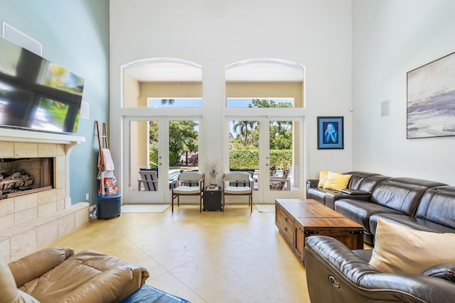 living room featuring light tile patterned flooring, a towering ceiling, french doors, and a fireplace