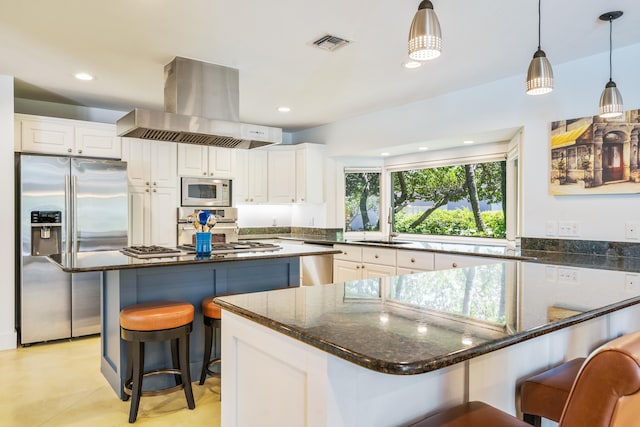 kitchen featuring dark stone countertops, exhaust hood, stainless steel appliances, pendant lighting, and white cabinets