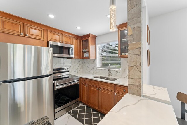 kitchen with appliances with stainless steel finishes, backsplash, sink, pendant lighting, and light tile patterned floors