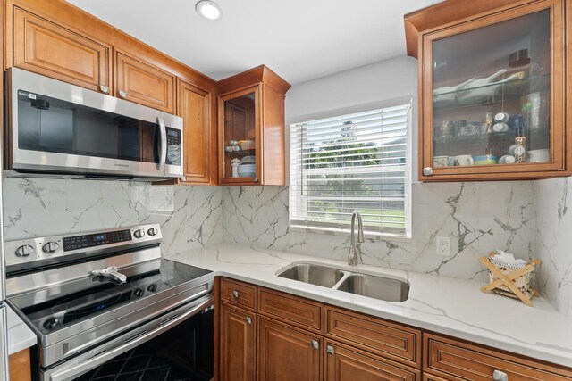 kitchen with sink, backsplash, light stone countertops, and stainless steel appliances