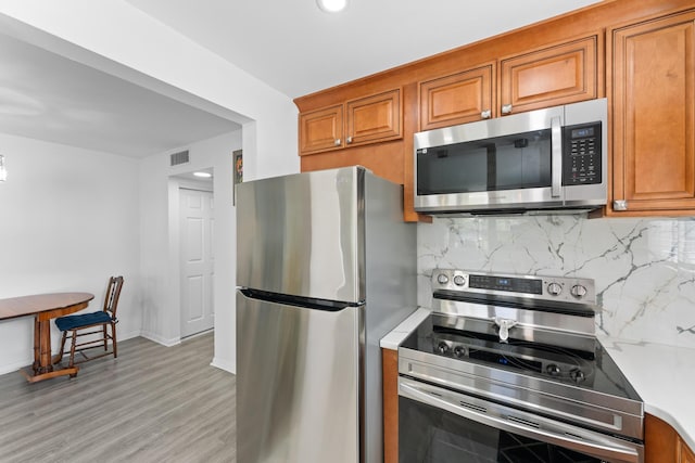 kitchen featuring decorative backsplash, light hardwood / wood-style floors, and stainless steel appliances