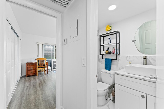 bathroom featuring hardwood / wood-style flooring, toilet, vanity, and tile walls