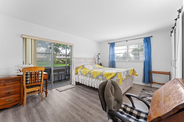 bedroom featuring baseboards, wood finished floors, and access to exterior