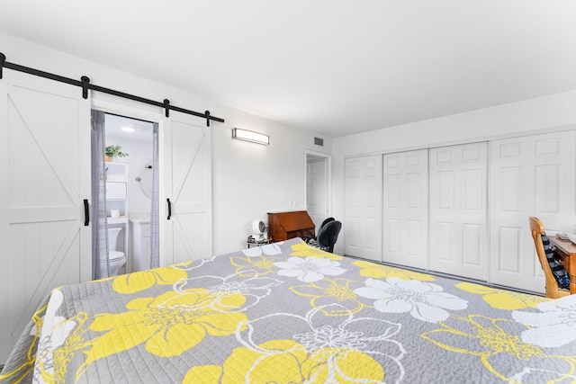 bedroom featuring a closet, ensuite bath, and a barn door