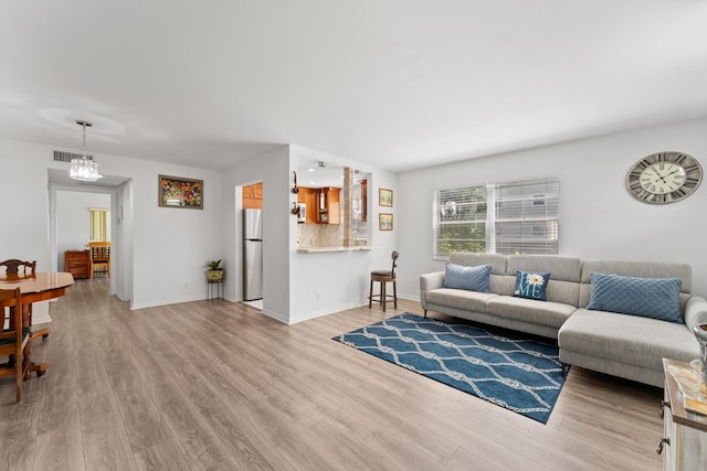 living room featuring an inviting chandelier and light hardwood / wood-style flooring