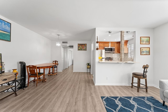 living area featuring light wood-style flooring, visible vents, baseboards, and a chandelier