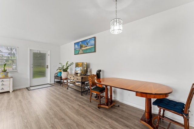 dining space with baseboards, a notable chandelier, and wood finished floors