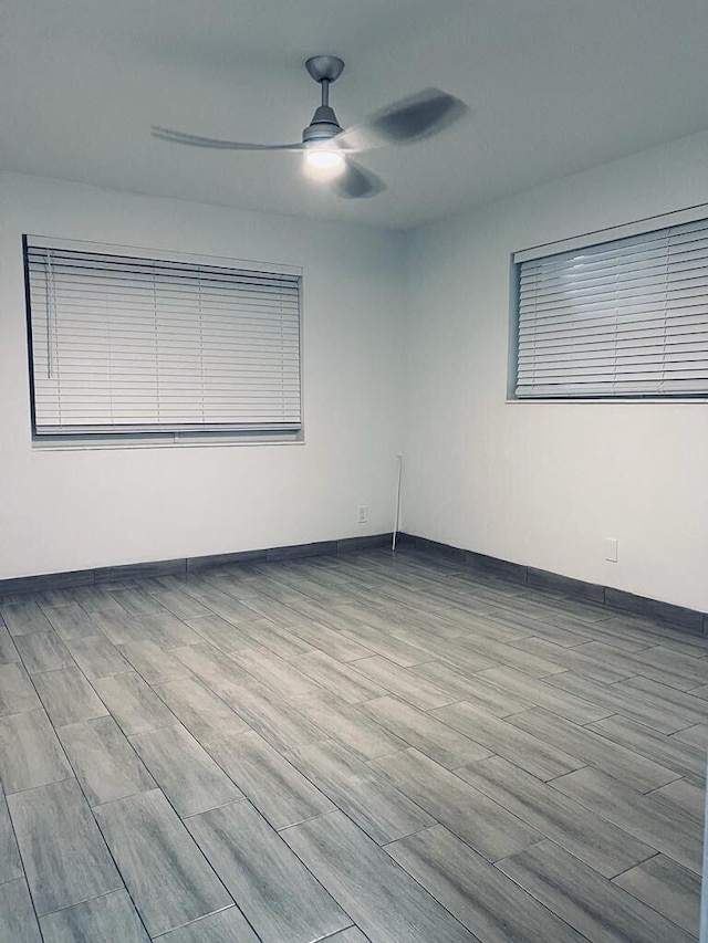 empty room featuring a ceiling fan, baseboards, and wood finished floors