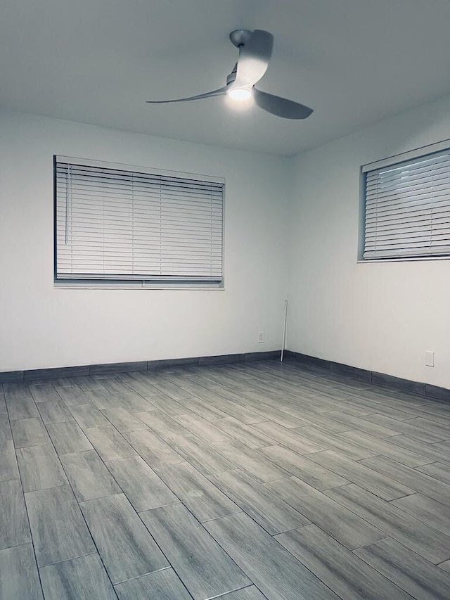 empty room featuring wood finished floors, a ceiling fan, and baseboards