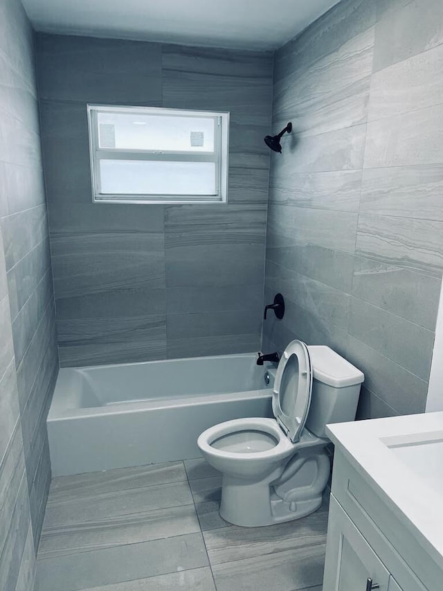 bathroom with  shower combination, tile walls, vanity, and toilet