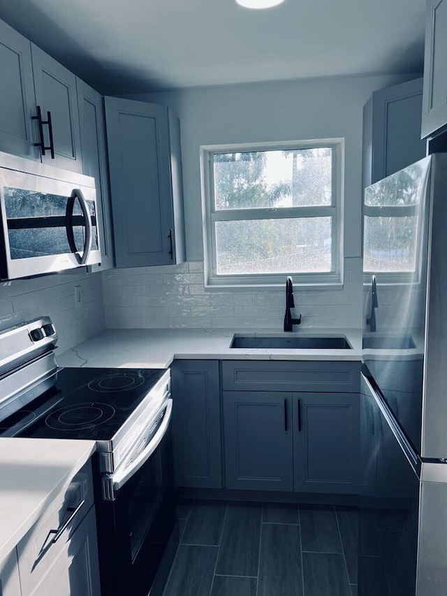 kitchen featuring stainless steel appliances, backsplash, a sink, and light countertops