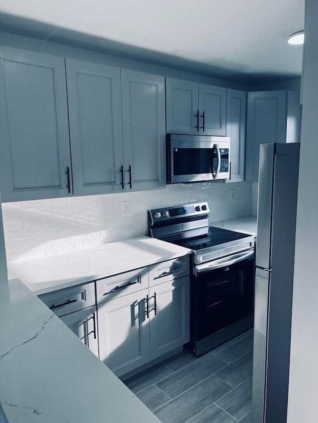 kitchen featuring tasteful backsplash, appliances with stainless steel finishes, and light stone counters