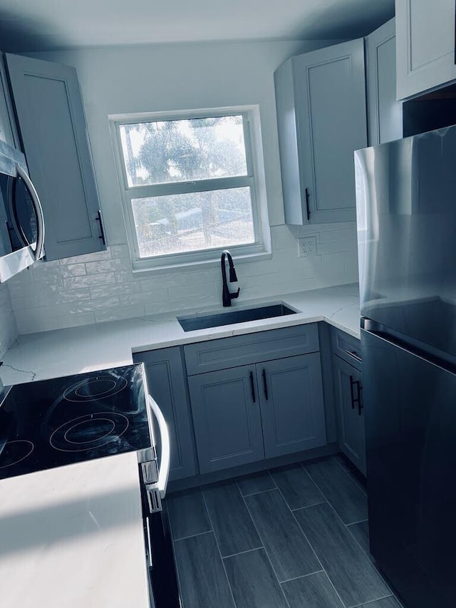 kitchen with light countertops, decorative backsplash, appliances with stainless steel finishes, wood tiled floor, and a sink