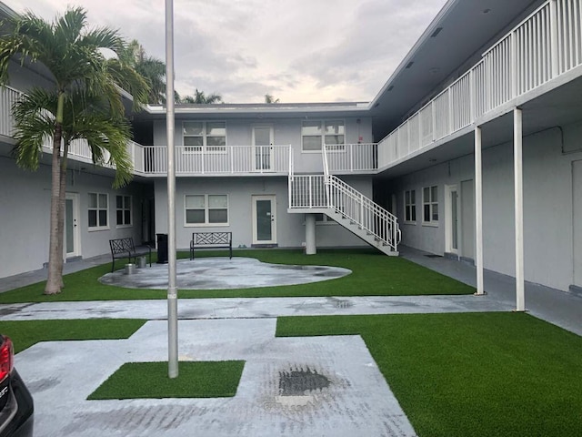 view of property's community featuring a patio area, a lawn, and stairway