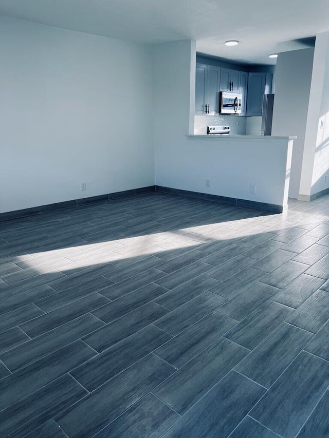 unfurnished living room with wood finish floors and baseboards