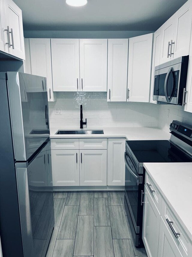 kitchen featuring appliances with stainless steel finishes, white cabinets, sink, and backsplash