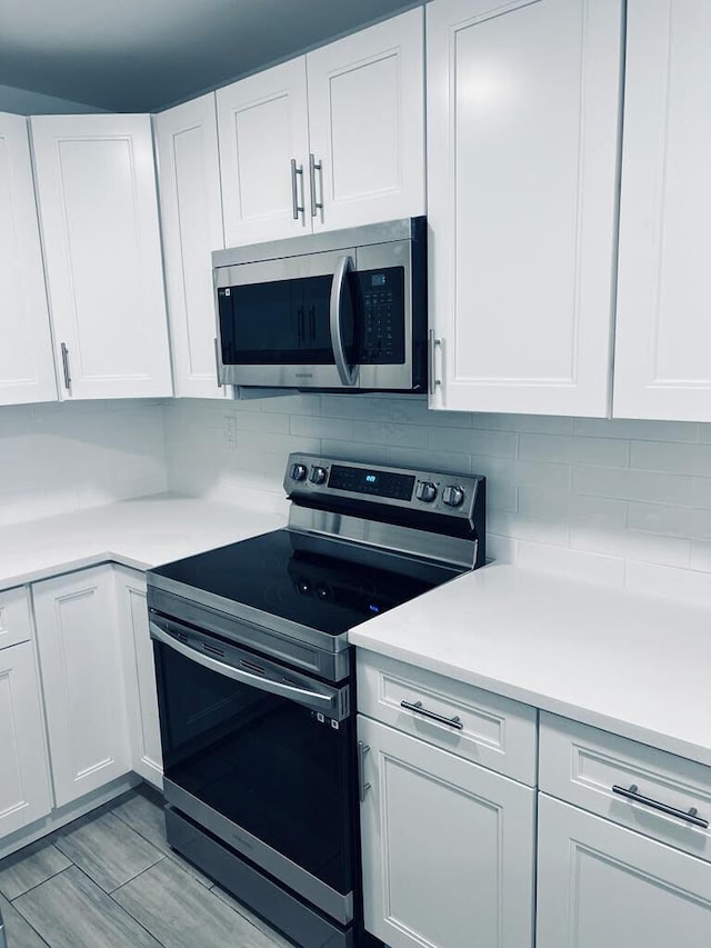 kitchen with white cabinetry, appliances with stainless steel finishes, light countertops, and backsplash