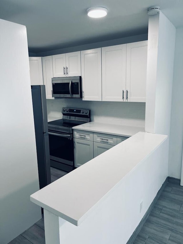 kitchen with stainless steel appliances, light countertops, and white cabinets