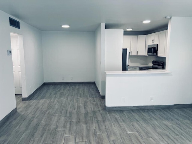 kitchen featuring light countertops, appliances with stainless steel finishes, wood finish floors, and white cabinets