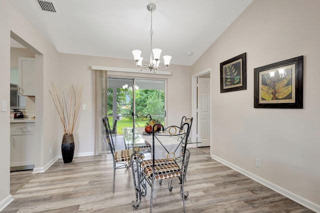 dining area with light hardwood / wood-style floors, a chandelier, and vaulted ceiling