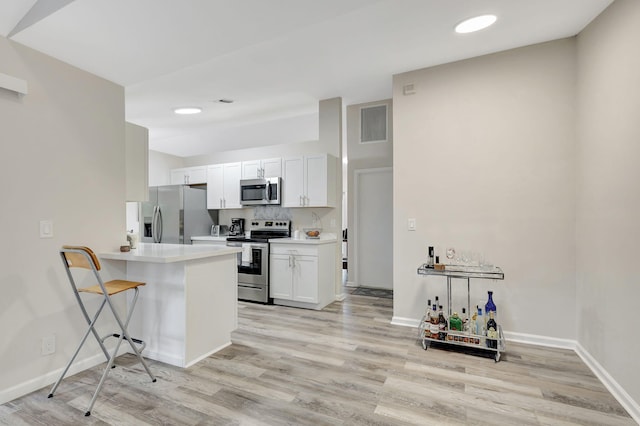 kitchen with decorative backsplash, white cabinets, a breakfast bar, light hardwood / wood-style floors, and stainless steel appliances