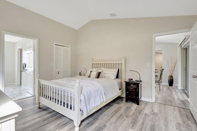 bedroom featuring light hardwood / wood-style flooring, lofted ceiling, and a closet