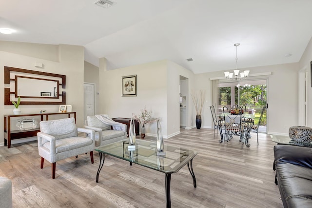 living room with light wood-type flooring, a notable chandelier, and lofted ceiling