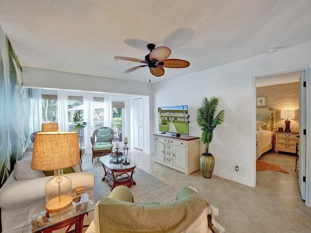 living room featuring a textured ceiling, ceiling fan, and light tile patterned flooring