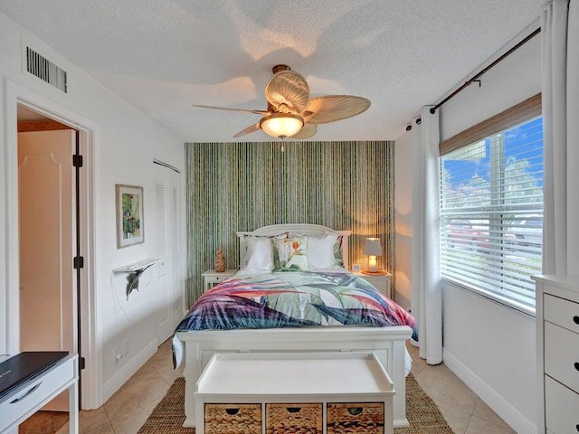 bedroom featuring a textured ceiling, ceiling fan, and light tile patterned flooring