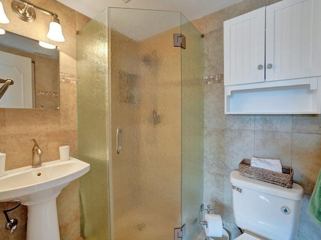 bathroom with tile walls, toilet, and a shower with door