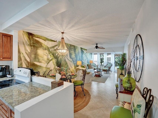 kitchen with hanging light fixtures, ceiling fan with notable chandelier, white electric range, light tile patterned floors, and a textured ceiling