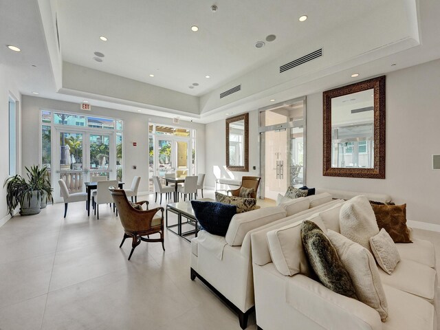 living room featuring light tile patterned floors, a raised ceiling, and french doors