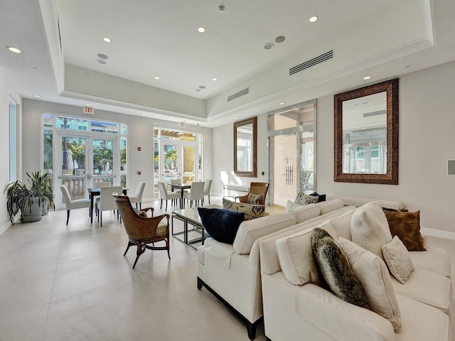 living room featuring visible vents, french doors, a raised ceiling, and baseboards