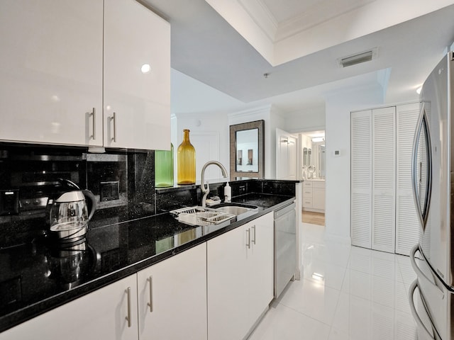 kitchen featuring white cabinetry, appliances with stainless steel finishes, light tile patterned floors, sink, and dark stone countertops