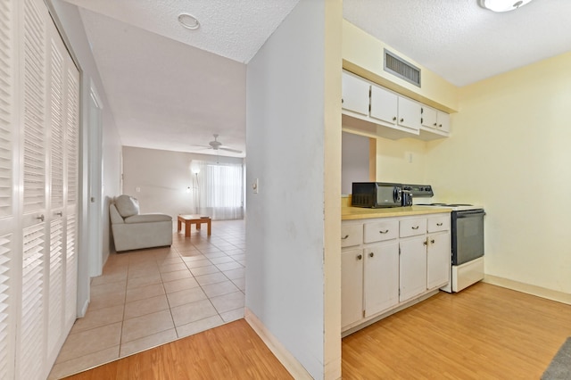 kitchen featuring white cabinets, light wood-type flooring, white electric stove, and a textured ceiling