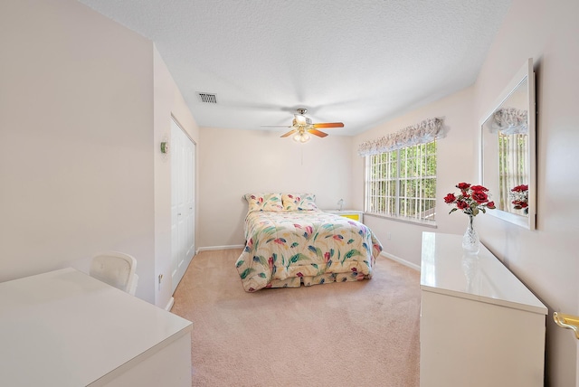 carpeted bedroom with a textured ceiling, a closet, and ceiling fan