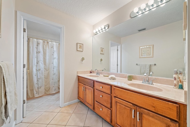 bathroom featuring tile patterned flooring, a textured ceiling, and double sink vanity