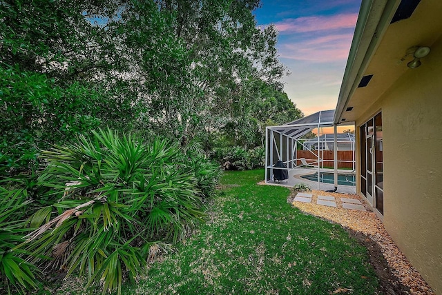 yard at dusk featuring a lanai